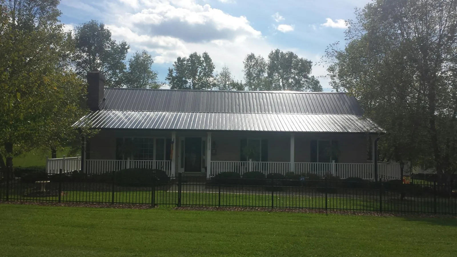 Gray metal roof on a brick ranch with a full width front porch — Gutter Guard Installation work by our crew in West Palm Beach