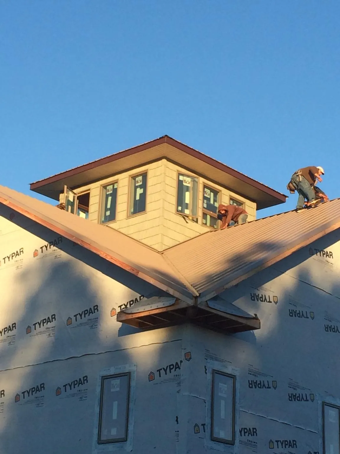 Roofers working around a rooftop cupola on a new metal roof at sunset — Roof Waterproofing in West Palm Beach by Roofing Brothers